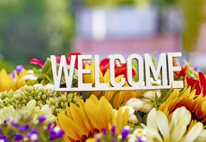 Welcome sign displayed among a colorful arrangement of flowers.